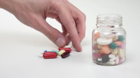 Man's hand neatly puts pills in a jar. Pharmacy