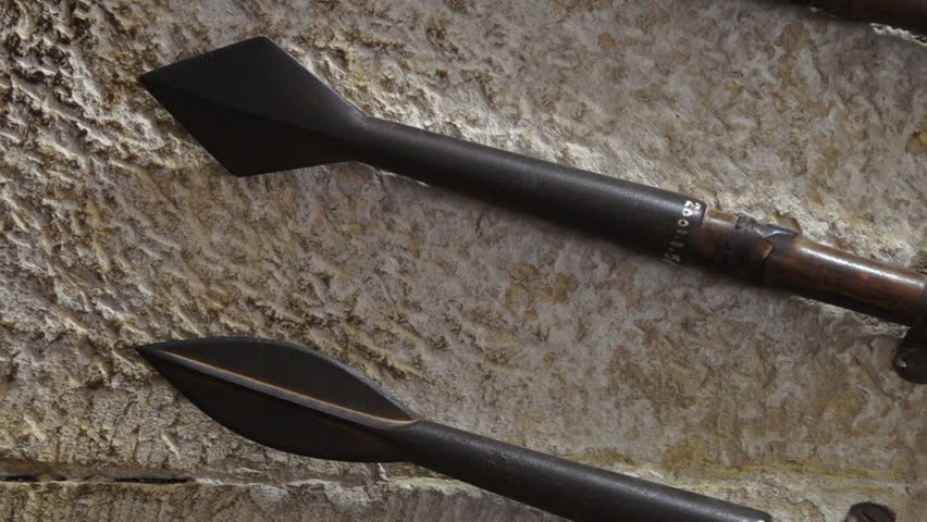 Side view of old spears with wooden handles hung on a wall