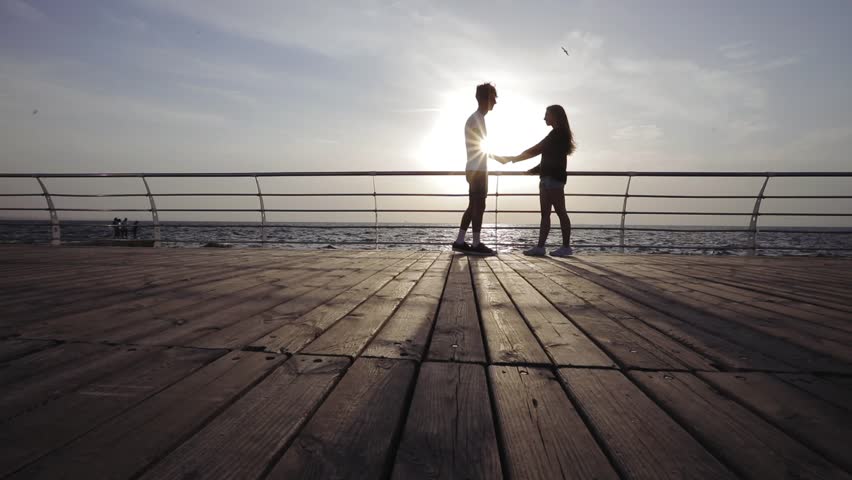 Silhouette of a couple in love. Romantic couple kissing on the beach. Contraception, first love, protection