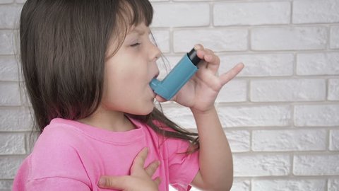 Kid suffering from pain because of asthma. Child doing asthma inhalation.