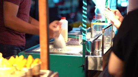 A street hawker is preparing fried ice cream for customers at Jalan Alor Night Market, Bukit Bintang. A famous tourists attraction.