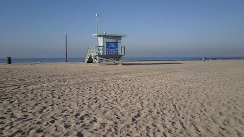 Lifeguard Tower at Venice Beach LA seagulls and surfers in aerial drone view. 4k shot of sand and waves in pacific ocean. Sunny morning in Los Angeles, California