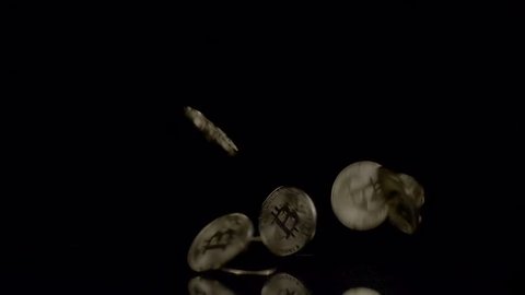 Bitcoins Crypto Currency falling on a reflective surface. Black backgound