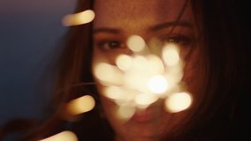close up sparklers portrait of beautiful caucasian woman celebrating new years eve enjoying independence day celebration on beach at sunset - Powered by Shutterstock - Get 15% off with code: PIKWIZARD15