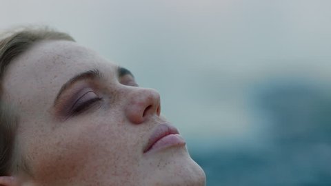 close up portrait of beautiful young woman looking up praying exploring spirituality contemplating future on cloudy seaside