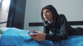 young teen and joystick man hooded sweater absorbed In online video game. boy teenager in the hood playing lifestyle video games on the console on the gamepad. Controller console gamepad. Gaming man