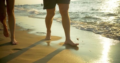 Couple Walks Barefoot on Beach