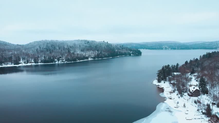 Aerial view from drone flying above cottage at Eagle Lake on a cold winter day, Haliburton County, Ontario, Canada