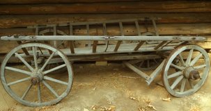 Old fashioned. wooden horse cart for farm use is parked beside the wall of a log cabin on a rural farm in Ukraine. 4k DCI stock footage