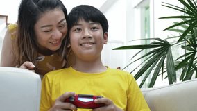 Asian mother and son playing video game at home together.4K Slow motion