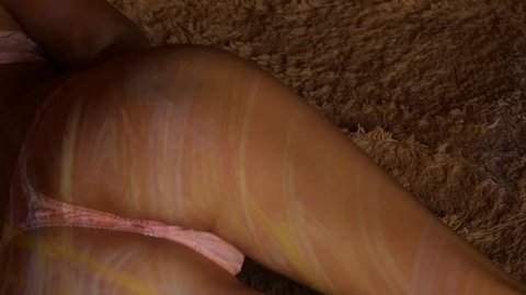 Beautiful sexy ass in pink panties on a bed with striped shadow. Attractive female body resting in a hotel room. slow motion