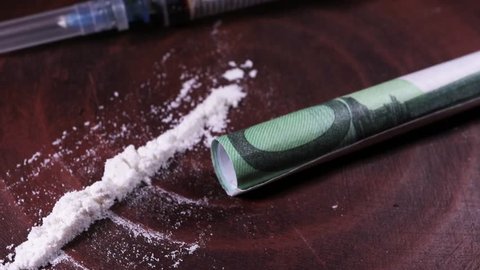 syringe, drug, powder Euro money twisted into a tube revolve on a clay background