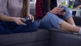 female teenager winning videogame competition with girlfriend sitting on sofa on backgrounf of company at home party