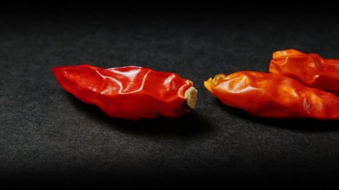 Dolly shot on some spicy chili peppers resting on a black background.