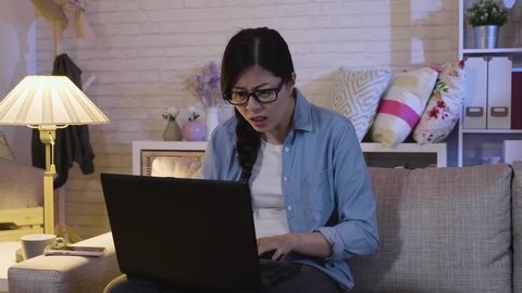 young office lady sitting in sofa with notebook frustrated worried frowning with computer cased problem. elegant businesswoman working hard staying up late at home. annoyed girl with shut down laptop