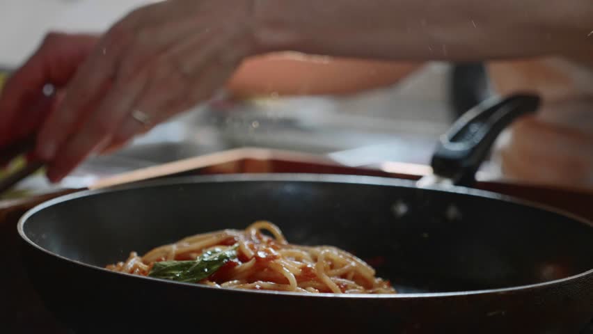 Cooking and stirring the spaghetti with red tomato sauce in the frying pan, close-up in slow motion | Shutterstock HD Video #1021204648