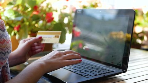 Hand holding credit card with inscription "Gold card" on notebook background. Buy online and payment concept with bank card. Woman paying online with banking card and computer