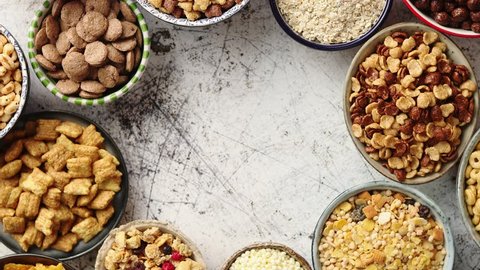 Assortment of various kinds cereals placed in ceramic bowls with cornflakes, granola, cereals and oatmeal. Flat lay, top view on white rusty table with copy space in the middle