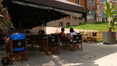 Barcelona, SPAIN - AUGUST, 12, 2018: People at restaurant of Hospital Sant Pau. Asian tourists have lunch at 902 Caf Modernista outside, hot summer day.