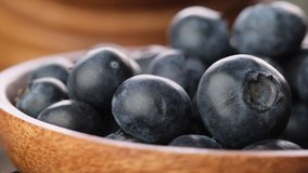 Close up footage of blueberry fruits in wooden bowl. Selective focus.