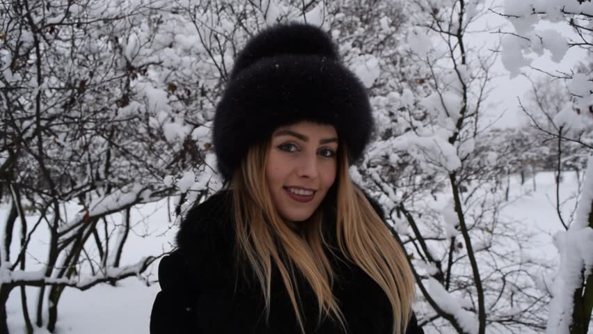 Portrait of a young beautiful girl in black on the background of winter nature

