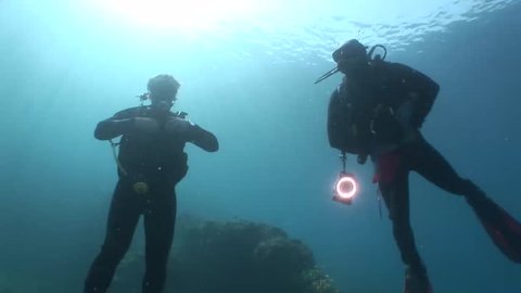 scuba diver photographers coming up surface safety stop ascending underwater