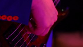 musician plays bass guitar in discolights. close up. music video recording