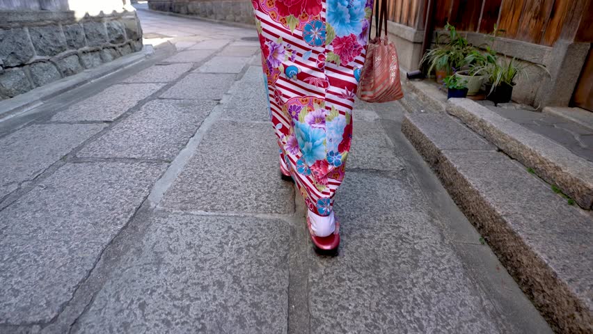 down to up back view of geisha walking on a street of ishibe alley. local woman wearing kimono cardigan going home in town surrounding by wooden house in Kyoto Japan. japanese lady festival lifestyle
