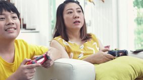 Asian mother and son playing video game at home together.4K Slow motion of happy family playing with smile face.