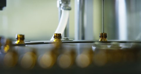 Close up of production of medicines in glassware bottles on automatic lines in a pharmaceutical factory. Concept of healthcare, pharmaceutical industry, medicine production