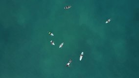 Bird's-eye drone footage of surfers in clear water with reef underneath in Uluwatu, Bali Indonesia