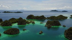 Drone flying over a group of small tropical islands on the coast of Raja Ampat, Indonesia