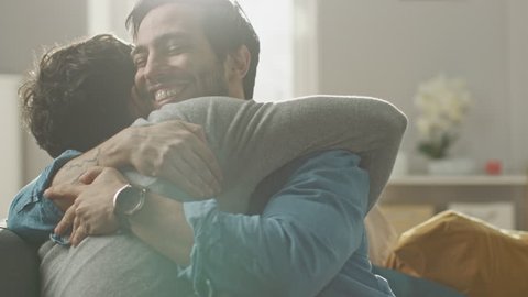 Gay Marriage Proposal Concept. Adorable Boyfriend Gifts a Beautiful Shiny Wedding Ring to His Cute Hispanic Fiance. Surprised Partner is Extremelly Happy and Hugs His Queer Friend. Relationship Goals.