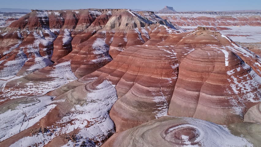 Slowly flying over red desert looking at the layers with snow melting in the Utah Badlands.