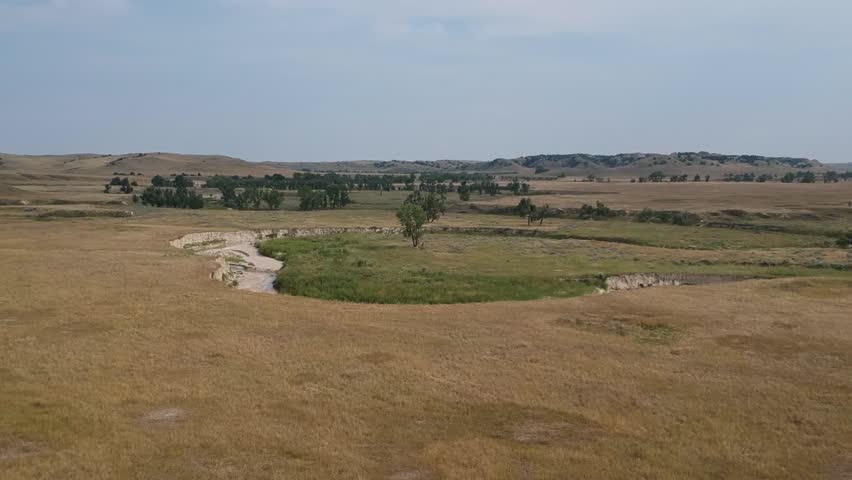 Aerial drone shot panning up and across rolling hills, plains, and wash in South Dakota.