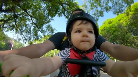 Father with baby riding a bicycle in the park. Ibirapuera park in Sao Paulo city. 4K 60fps.
