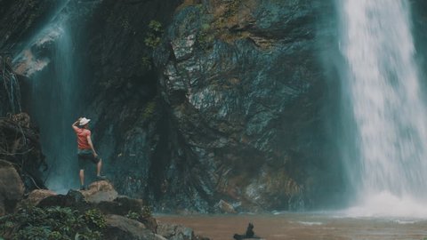 Active lifestyle and travel concept: Traveler man enjoy unbelievable waterfall in the form of a pirate skull and bones in the tropical jungle