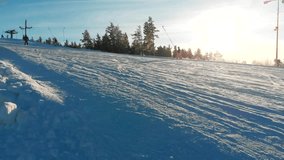 Aerial video of skiers and snowboarders going down the slope in winter day. Winter Sports. Skiers and snowboarders on ski resort in winter season. 4K video, aerial footage.