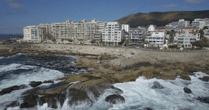4K summer day aerial drone footage of spectacular popular bathing Saunders Rock's Beach, residential suburb of Cape Town on the Atlantic seaboard of the Cape Peninsula in Western Cape in South Africa