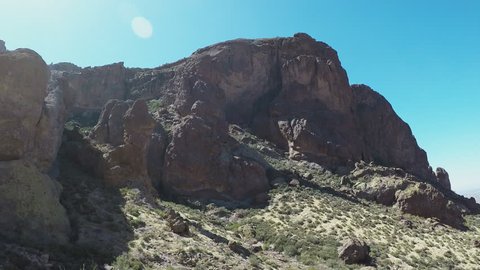 Apache Junction, AZ / USA - July 12, 2018: Pan shot to hikers descending from Superstition Mountain. Clip reveals a small group of people walking down a rocky trail from the hills above.
