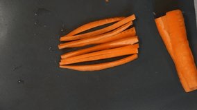 Chef cuts carrot. Cooking process. Hands cutting carrot. Chef slices the carrot