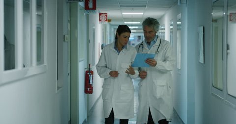 Doctor and nurse discussing the diagnosis of a patient for the future advice for his treatment during walking in a hospital ward. Concept of medicine, technology, health care and people, hospital
