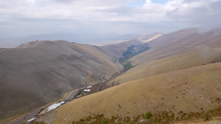 Looking down from a mountain top to a lonely road in the valley below with one car driving along the road