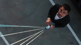 Big City Businessman Uses Smartphone, Stands on Skyscraper Roof: Visualization of Information Flows and Lines Flying from Mobile Phone into Global Network. Top Down Aerial Elevating Drone Shot. - Powered by Shutterstock - Get 15% off with code: PIKWIZARD15