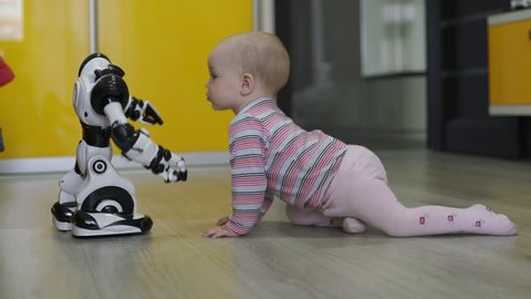 The little girl carefully looks at the toy robot and dances with him. Modern Robotic Technologies