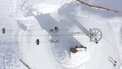 Top view from drone ski lift for transportation skiers and snowboarders on snowy slope. Ski elevator cable way for people transportation on winter mountain in resort. Winter skiing and snowboarding