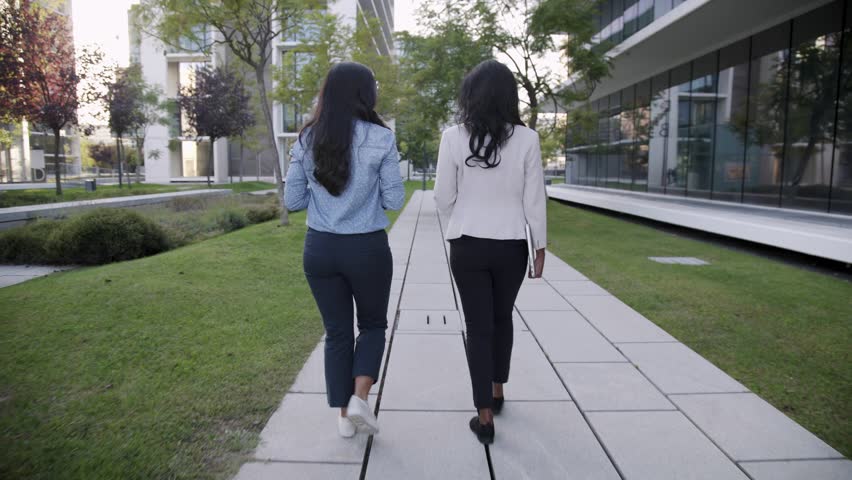 Professional businesswomen talking during walk, back view. Executive colleagues discussing work while walking in city park. Conversation concept Royalty-Free Stock Footage #1021319689