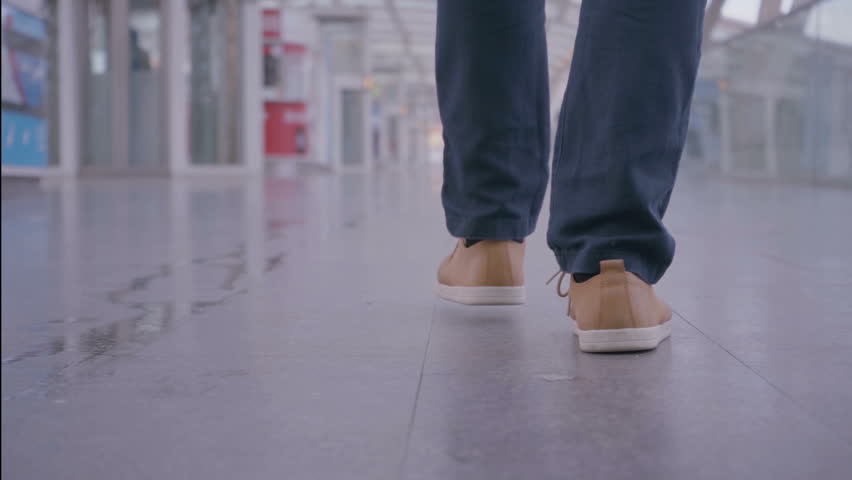 Cropped view of man in sneakers walking in light corridor. Low section view of stylish man walking indoor with copy space. Walk concept Royalty-Free Stock Footage #1021320016