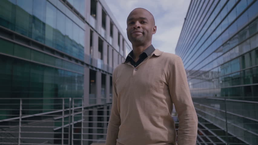 Successful African American manager posing with crossed arms. Confident businessman in casual clothing looking at camera near office building. Business concept Royalty-Free Stock Footage #1021320034