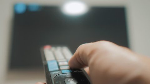 man hand holding the TV remote control and turn off smart tv. Channel surfing. Close up mans hand lifestyle holding TV remote control and changing TV channels. blurred background
